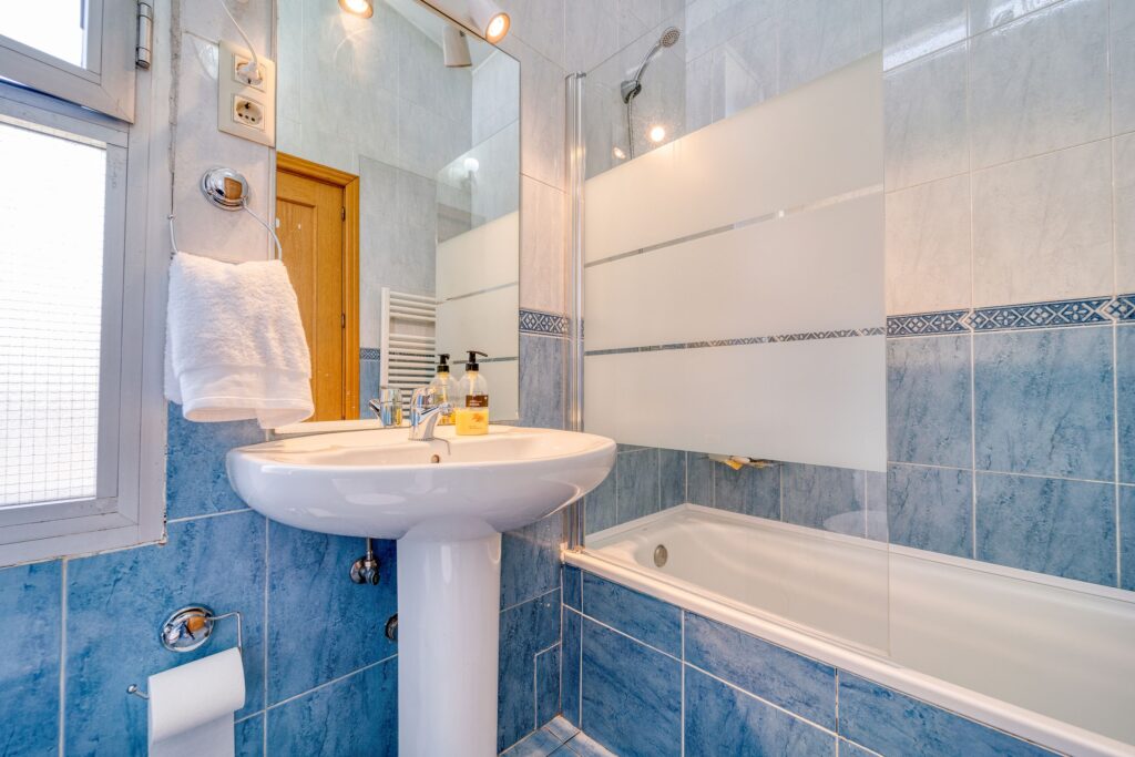 pexels-photo-12870169-12870169 Bright minimalist bathroom with modern blue tiles, glass shower, and a clean white sink.